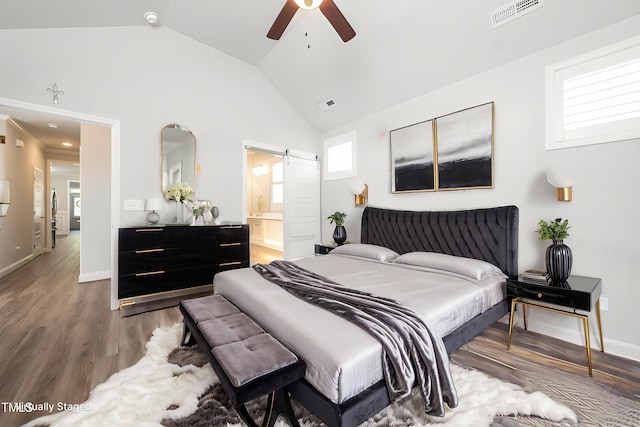 1705 Main Divide Dr, Wake Forest, NC 27587 - bedroom featuring a barn door, vaulted ceiling, wood finished floors, ensuite bath, and a ceiling fan