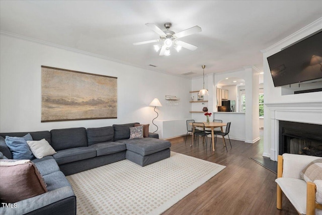 4826 Sir Duncan Way, Raleigh, NC 27612 - living area with arched walkways, a ceiling fan, dark wood-type flooring, crown molding, and a fireplace with raised hearth
