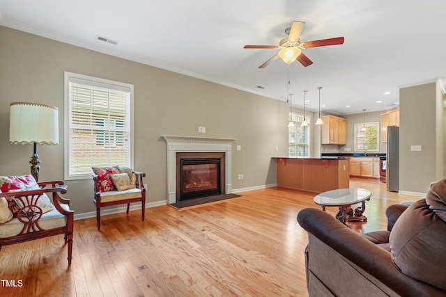 127 Bobwhite Way, Mebane, NC 27302 - living area featuring crown molding, light wood-style floors, a ceiling fan, a fireplace with flush hearth, and baseboards