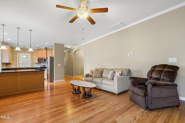 127 Bobwhite Way, Mebane, NC 27302 - living room with crown molding, light wood-style floors, arched walkways, a ceiling fan, and baseboards