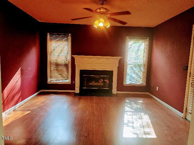 5301 Peacenest Dr, Raleigh, NC 27610 - unfurnished living room with ceiling fan, baseboards, a fireplace with flush hearth, and wood finished floors