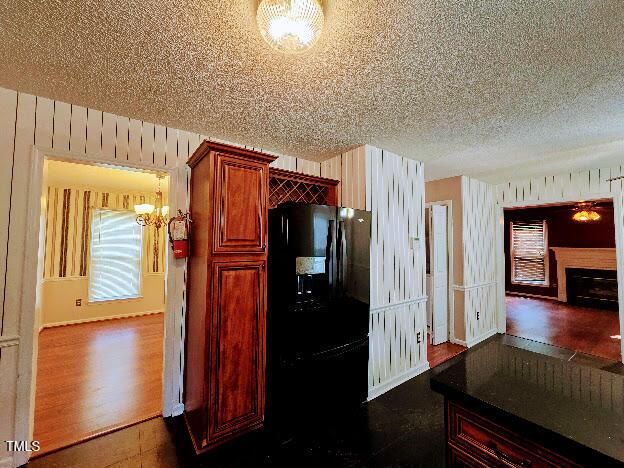 5301 Peacenest Dr, Raleigh, NC 27610 - kitchen featuring freestanding refrigerator, a chandelier, a textured ceiling, dark wood-type flooring, and a fireplace