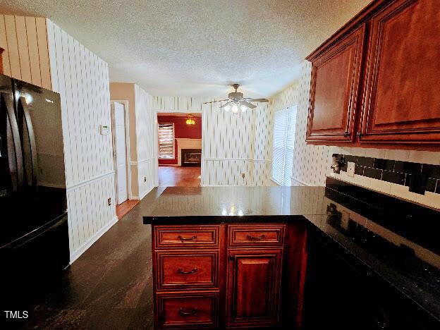 5301 Peacenest Dr, Raleigh, NC 27610 - kitchen with freestanding refrigerator, dark brown cabinets, wallpapered walls, a peninsula, and a textured ceiling