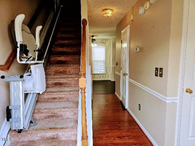 5301 Peacenest Dr, Raleigh, NC 27610 - stairway featuring a textured ceiling, wood finished floors, baseboards, and ceiling fan