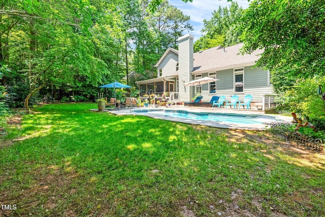 7401 Heartland Dr, Wake Forest, NC 27587 - back of house featuring a sunroom, an outdoor pool, a chimney, a patio area, and a lawn