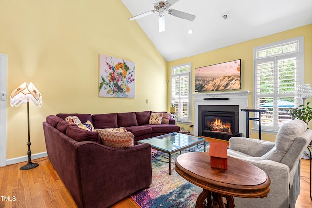 7401 Heartland Dr, Wake Forest, NC 27587 - living room featuring a ceiling fan, high vaulted ceiling, a glass covered fireplace, light wood-style floors, and baseboards