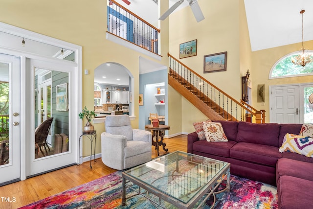 7401 Heartland Dr, Wake Forest, NC 27587 - living room featuring a towering ceiling, light wood-style flooring, stairs, a ceiling fan, and a chandelier