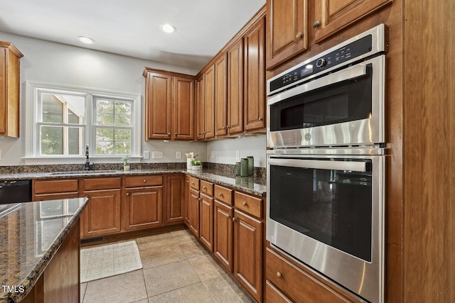 825 Highwater Pl, Fuquay Varina, NC 27526 - kitchen featuring stainless steel double oven, brown cabinetry, dark stone countertops, and recessed lighting
