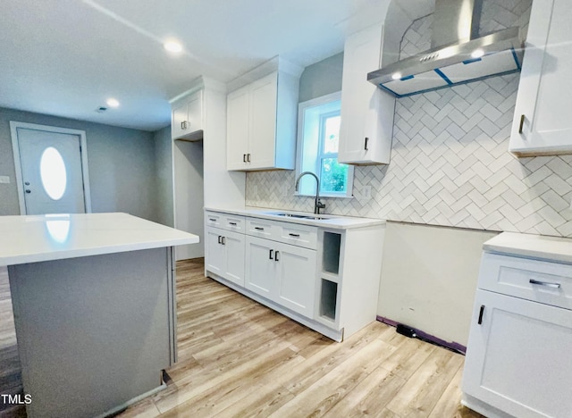 505 E Canary St, Dunn, NC 28334 - kitchen with wall chimney exhaust hood, light wood-style floors, a sink, backsplash, and white cabinets