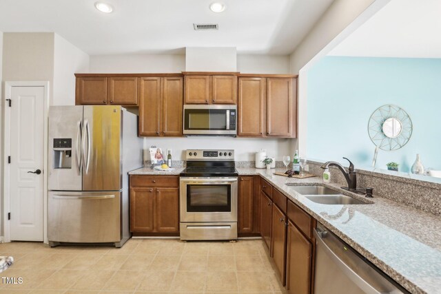 8204 Yaxley Hall Dr, Raleigh, NC 27616 - kitchen featuring stainless steel appliances, a sink, light stone countertops, brown cabinets, and recessed lighting