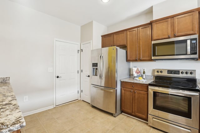 8204 Yaxley Hall Dr, Raleigh, NC 27616 - kitchen featuring stainless steel appliances, brown cabinets, light stone counters, and baseboards