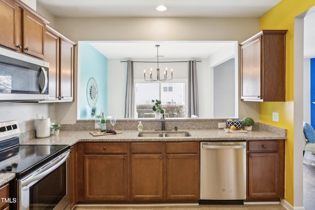 8204 Yaxley Hall Dr, Raleigh, NC 27616 - kitchen with stainless steel appliances, a sink, a chandelier, light stone counters, and brown cabinetry