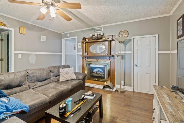 819 Corbin St, Albemarle, NC 28001 - living room featuring wood finished floors, a ceiling fan, a textured ceiling, a fireplace with raised hearth, and crown molding