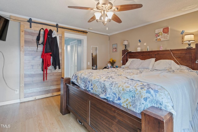 819 Corbin St, Albemarle, NC 28001 - bedroom featuring light wood finished floors, ornamental molding, a barn door, a ceiling fan, and baseboards