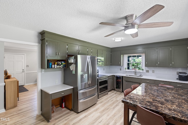 509 Forest Ridge Rd, Garner, NC 27529 - kitchen with appliances with stainless steel finishes, wine cooler, light wood finished floors, tasteful backsplash, and a ceiling fan