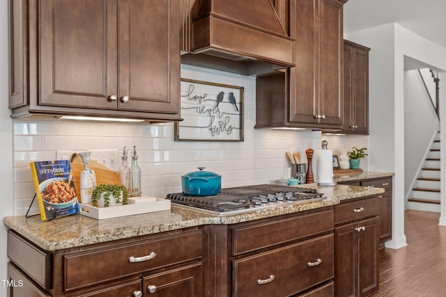3032 Curling Creek Dr, Apex, NC 27502 - kitchen with stainless steel gas cooktop, premium range hood, tasteful backsplash, and dark brown cabinetry