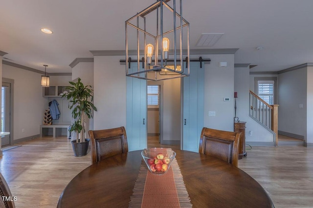 1624 Tunnel St, Wendell, NC 27591 - dining area with wood finished floors, crown molding, a barn door, stairs, and a chandelier