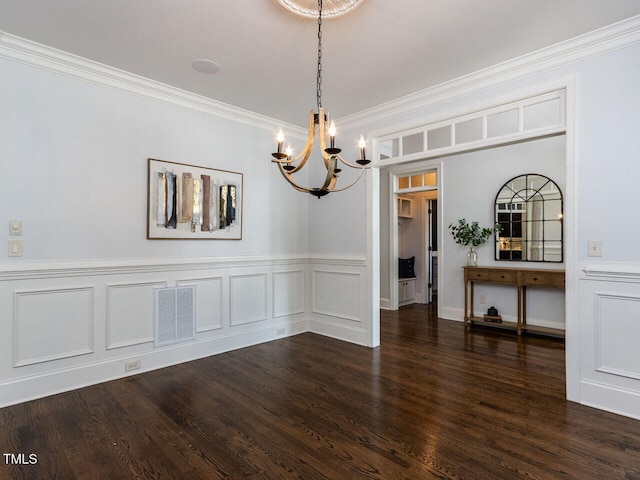 612 Peach Orchard Pl, Cary, NC 27519 - unfurnished dining area with a chandelier, crown molding, dark wood-type flooring, wainscoting, and a decorative wall