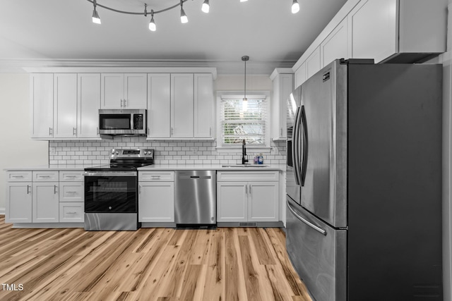 2913 Coxindale Dr, Raleigh, NC 27615 - kitchen featuring appliances with stainless steel finishes, light wood-style floors, light countertops, and white cabinets