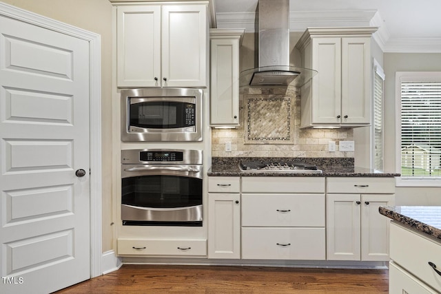 513 Goal Kick, Fuquay Varina, NC 27526 - kitchen featuring appliances with stainless steel finishes, wall chimney exhaust hood, ornamental molding, decorative backsplash, and dark stone counters