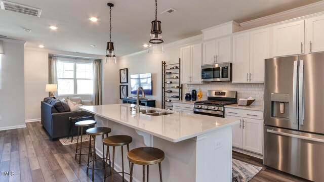 219 Carova Bnd, Apex, NC 27539 - kitchen featuring stainless steel appliances, a sink, an island with sink, white cabinetry, and crown molding