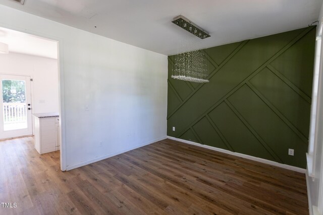 328 Mccarthy Dr, Clayton, NC 27527 - empty room featuring a decorative wall, wood finished floors, baseboards, and a chandelier