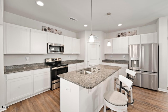 10 Forest Brook Way, Clayton, NC 27520 - kitchen featuring stainless steel appliances, a sink, white cabinets, wood finished floors, and recessed lighting