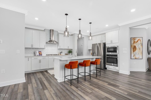 321 Calvander Ln, Apex, NC 27539 - kitchen featuring stainless steel appliances, wall chimney exhaust hood, crown molding, light countertops, and a kitchen bar