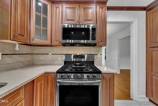 2204 Basil Dr, Raleigh, NC 27612 - kitchen featuring appliances with stainless steel finishes, crown molding, light stone countertops, glass insert cabinets, and brown cabinets