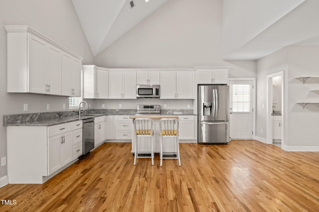 225 E End Ave, Durham, NC 27703 - kitchen featuring appliances with stainless steel finishes, white cabinetry, a sink, and high vaulted ceiling