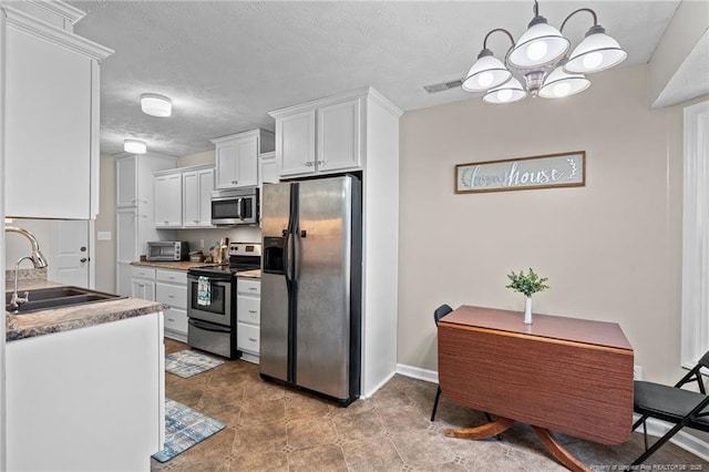 306 Longleaf Pines Dr, Raeford, NC 28376 - kitchen with stainless steel appliances, a sink, white cabinets, a chandelier, and a textured ceiling