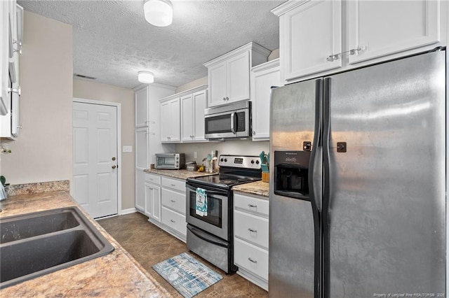 306 Longleaf Pines Dr, Raeford, NC 28376 - kitchen with stainless steel appliances, a sink, white cabinets, a textured ceiling, and light countertops