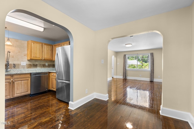 2712 Broad St, Durham, NC 27704 - kitchen featuring stainless steel appliances, arched walkways, light stone countertops, dark wood finished floors, and baseboards