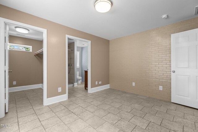 2712 Broad St, Durham, NC 27704 - unfurnished bedroom featuring brick wall, a spacious closet, baseboards, a closet, and ensuite bathroom