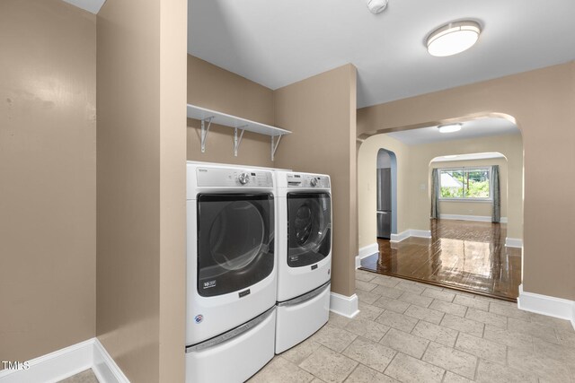 2712 Broad St, Durham, NC 27704 - washroom featuring arched walkways, washing machine and dryer, baseboards, and stone tile floors