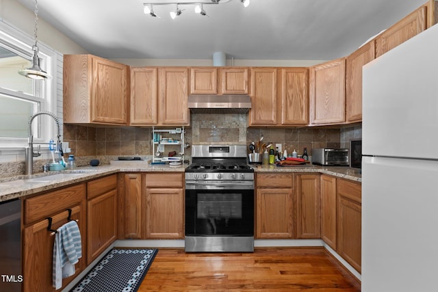 2710 Broad St, Durham, NC 27704 - kitchen featuring stainless steel appliances, a sink, under cabinet range hood, light wood-style flooring, and decorative backsplash