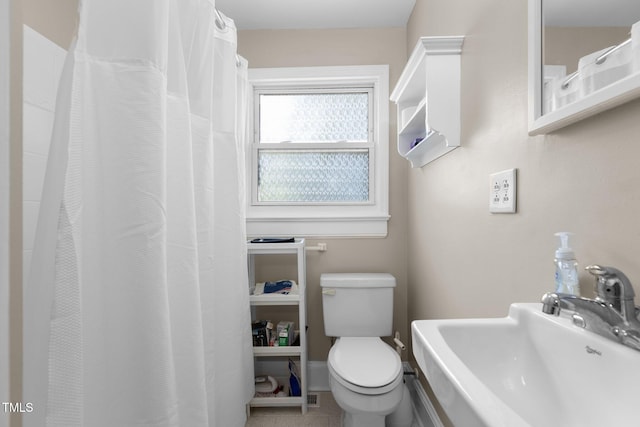 2710 Broad St, Durham, NC 27704 - bathroom featuring a sink, toilet, tile patterned flooring, and a shower with curtain