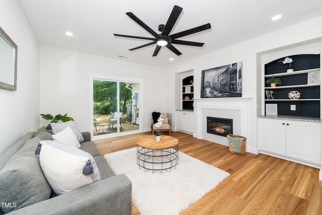 2001 Turtle Point Dr, Raleigh, NC 27604 - living room featuring light wood-style floors, a glass covered fireplace, ceiling fan, built in shelves, and recessed lighting