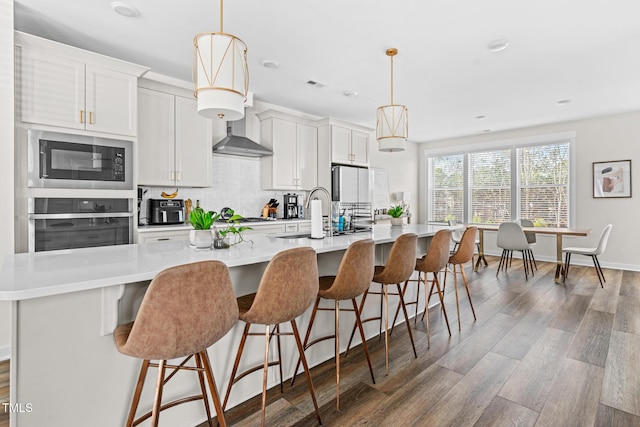 1203 Corkery Ridge Ct, Cary, NC 27519 - kitchen with stainless steel oven, a sink, built in microwave, wall chimney exhaust hood, and an island with sink