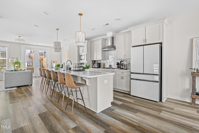 1203 Corkery Ridge Ct, Cary, NC 27519 - kitchen featuring freestanding refrigerator, wall chimney exhaust hood, a kitchen bar, wood finished floors, and light countertops