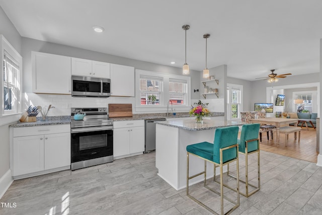 602 Dunbar St, Durham, NC 27701 - kitchen with stainless steel appliances, white cabinets, decorative backsplash, recessed lighting, and light stone counters