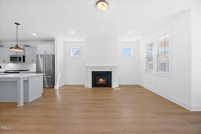 212 Aubey Ln, Wake Forest, NC 27587 - unfurnished living room with a lit fireplace, light wood-style flooring, baseboards, and recessed lighting