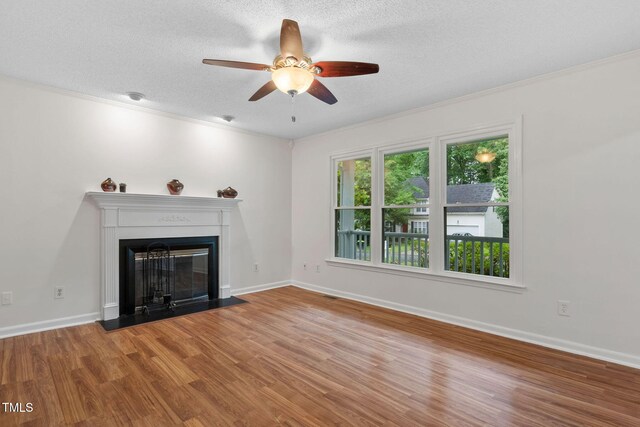 2724 Glastonbury Rd, Apex, NC 27539 - unfurnished living room featuring a ceiling fan, wood finished floors, a glass covered fireplace, a textured ceiling, and ornamental molding