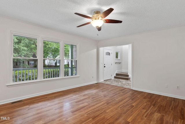 2724 Glastonbury Rd, Apex, NC 27539 - spare room with stairway, wood finished floors, a ceiling fan, a textured ceiling, and ornamental molding
