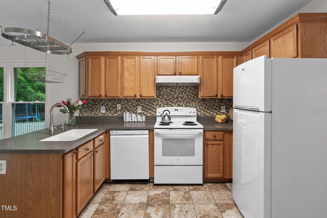 2724 Glastonbury Rd, Apex, NC 27539 - kitchen with white appliances, dark countertops, under cabinet range hood, a sink, and a textured ceiling
