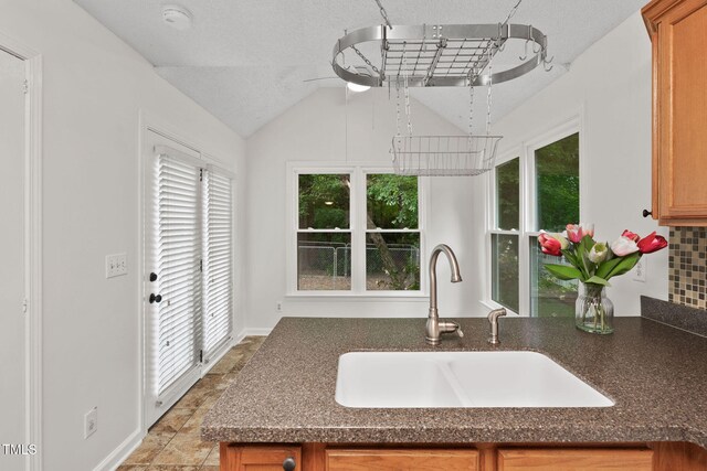 2724 Glastonbury Rd, Apex, NC 27539 - kitchen with a sink, healthy amount of natural light, brown cabinetry, and vaulted ceiling