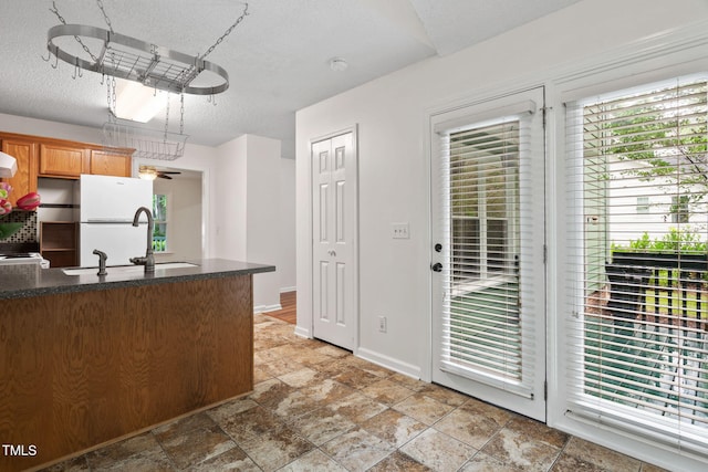 2724 Glastonbury Rd, Apex, NC 27539 - kitchen featuring a sink, light stone finish floors, a textured ceiling, freestanding refrigerator, and dark countertops