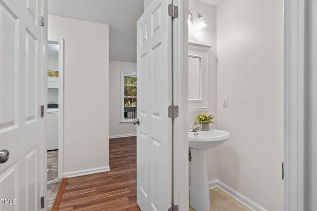 2724 Glastonbury Rd, Apex, NC 27539 - bathroom featuring baseboards, wood finished floors, washer / dryer, and a sink