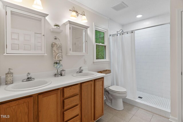 2724 Glastonbury Rd, Apex, NC 27539 - bathroom featuring a tile shower, double vanity, tile patterned flooring, toilet, and crown molding