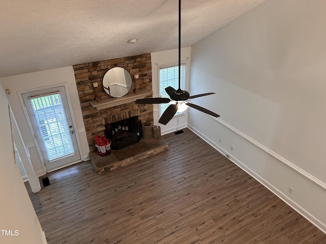 7832 Shuttle Rd, Fayetteville, NC 28311 - living room with a textured ceiling, dark wood-style floors, a stone fireplace, a ceiling fan, and baseboards